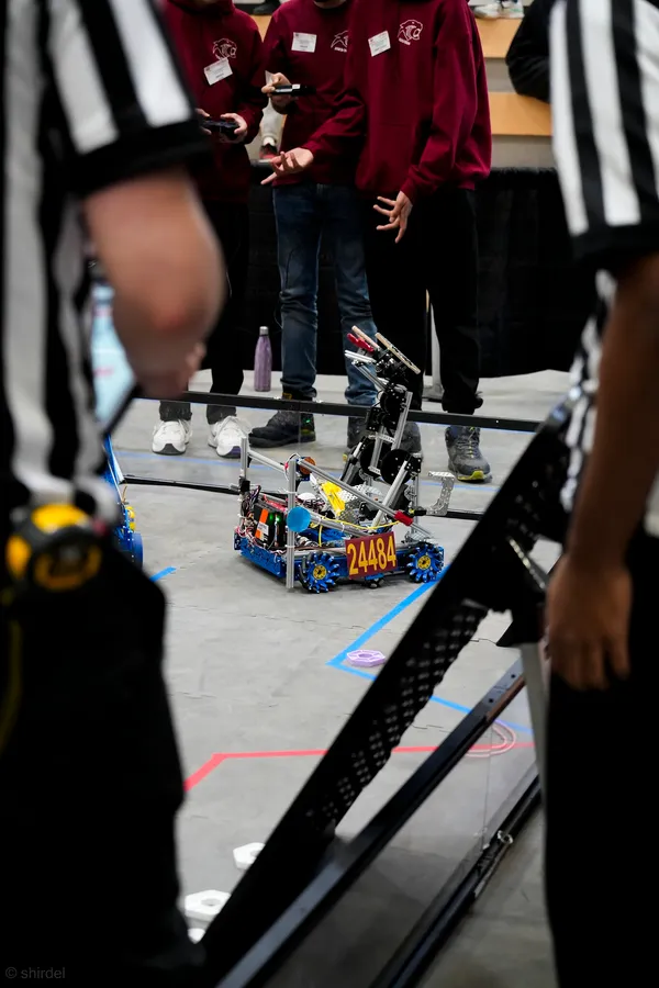 The Team 24484 FTC Robot at the Windsor Competition on the field, between 2 judges
