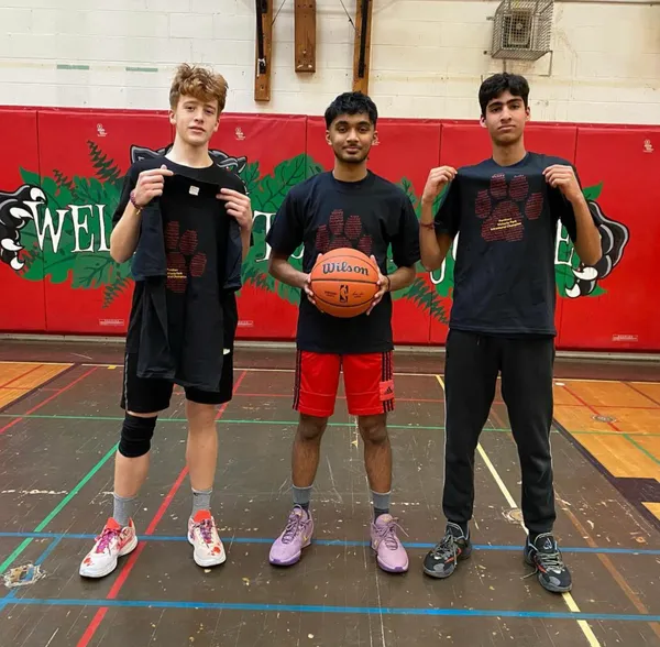 Three boys standing in Vic Parks' Gym 1 with a basketball in hand