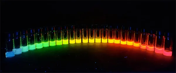 An assortment of rainbow-coloured chemicals glowing in glass vials.