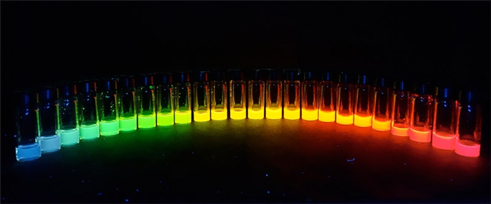 An assortment of rainbow-coloured chemicals glowing in glass vials.