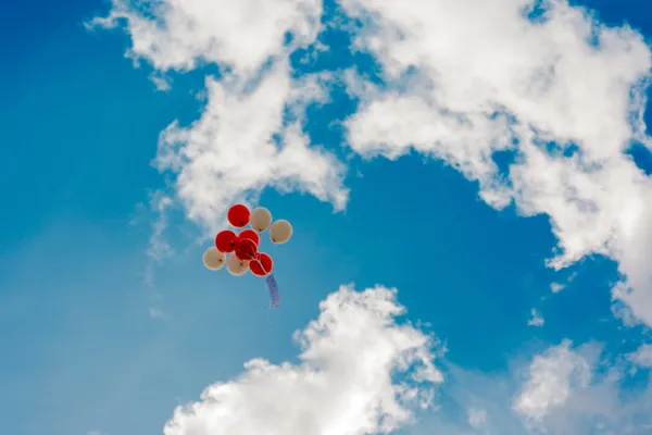 Red and beige balloons flying up in the sky
