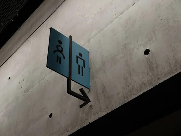 Public toilet sign on a concrete wall